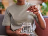 Frau wirft Brausetablette in ein Glas Wasser