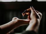 Frau tropft sich ein paar Tropfen Öl auf die Hand