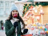 Frau isst einen Bratapfel auf dem Weihnachtsmarkt