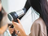 Frau föhnt sich die Haare