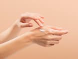 Frau trägt Handcreme mit Sonnenschutz auf ihre Hände auf