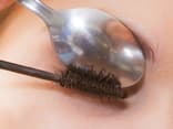 Frau biegt Wimpern mit Teelöffel