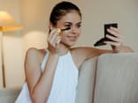 Brünette trägt Mascara mit Handspiegel auf