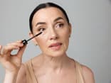 Frau trägt mit dem Mascara-Trick für Schlupflider Wimperntusche auf