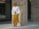 Eine Besucherin der Kopenhagen Fashion Week kombiniert silberne Sandalen zum Faltenrock