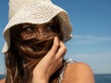 Frau trägt einen Sonnenhut am Strand