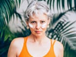 Frau mit grauen Haaren hat im Gesicht Sonnencreme aufgetragen