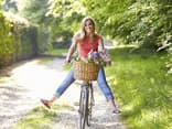 Eine junge Frau fährt bei schönem Wetter Fahrrad und ist glücklich