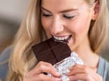 Frau isst Schokolade - ist Zucker ungesund für die Haut?