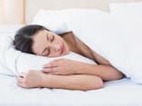 Ein Frau liegt im Bett und schläft - Tipps für das Schlafen, trotz Hitze gibt es hier.