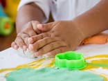 Kinderhände beim Selbermachen von Knete