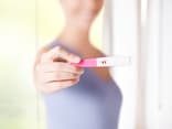 Frau zeigt ihren Schwangerschaftstest - Finden Sie hier Antworten auf 5 Fragen zur künstlichen Befruchtung 